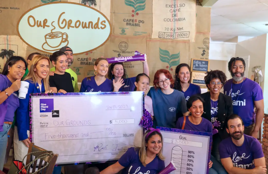 Commissioner Raquel Regalado and a diverse group celebrating a charitable donation at Our Grounds coffee shop.